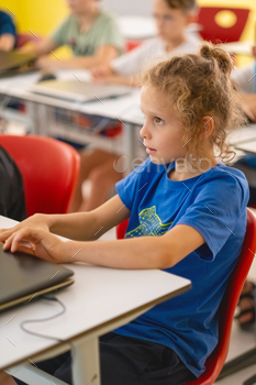 Elementary school student using computers in classroom at school.
