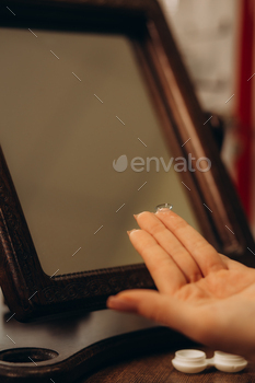 Young woman with contact lenses near mirror
