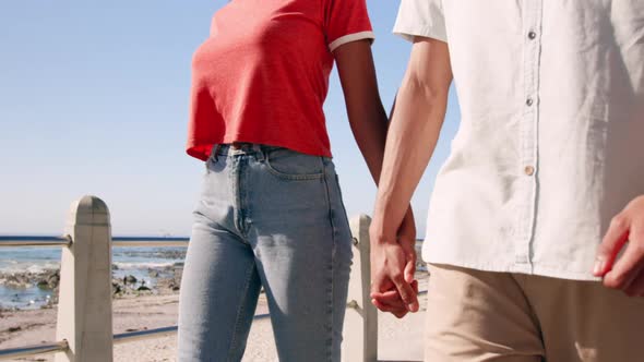 Couple holding hands and walking on beach promenade 4k