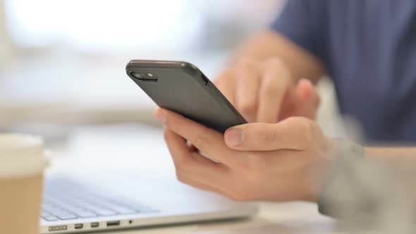 Close Up of Male Hands Using Smartphone Near Laptop