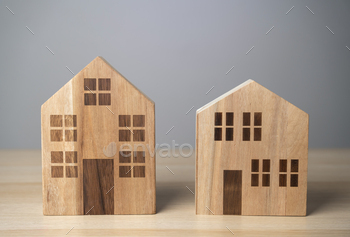 Two houses. Wooden figures. Buying and selling. Housing options. Buildings and infrastructure.