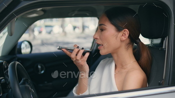 Businesswoman using voice recognition function smartphone sitting car close up.