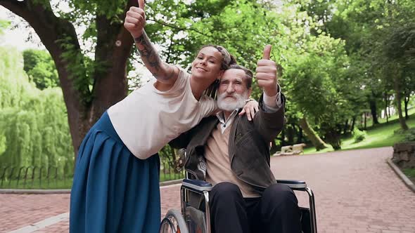 Granddaughter and Bearded Granddad in Wheelchair Looking at Camera