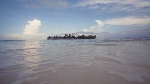 Little island with palms and building between water