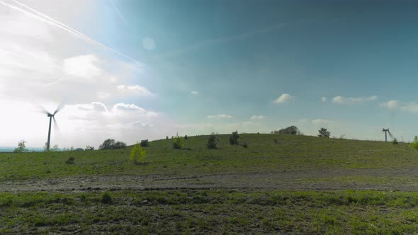 Electric wind turbine farm on top of old mining heap overgrown with grass, time lapse view