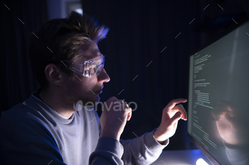 Focused Male Developer Coding Intently on a Computer in office at Night, looking at the screen