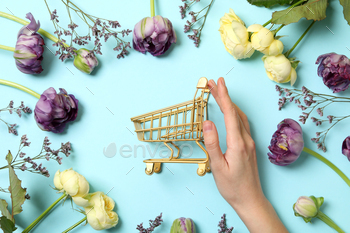 Shopping cart with flowers on a light background.