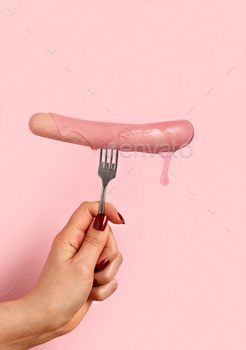 Hot sausages with pink sauce on fork pink background.