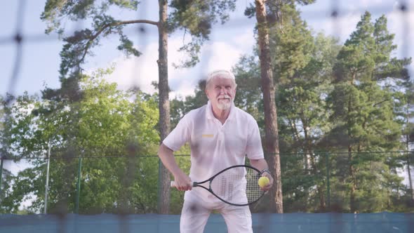 Joyful Happy Smiling Mature Man Playing Tennis on the Tennis Court