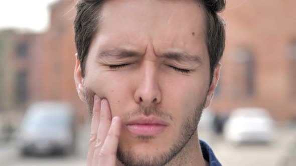 Outdoor Close Up of Young Man with Toothache