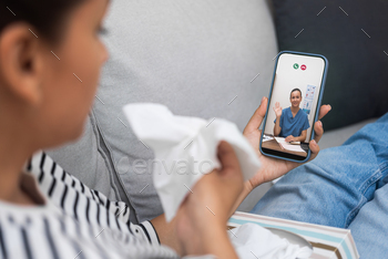 Telemedicine consult with a caring doctor on smartphone, patient at home with a cold