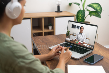 Patient with headphones engaged in a telemedicine session with a doctor on a laptop