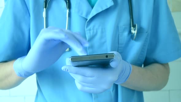 Doctor in Blue Gloves and Blue Runs on a Mobile Phone