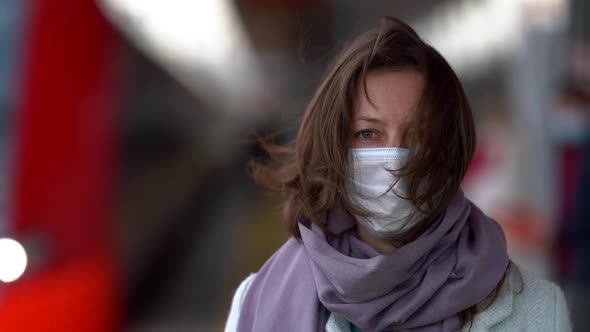 A Close-up of a Middle-aged Woman Standing on a Railway Platform on the Street. The Wind Blows