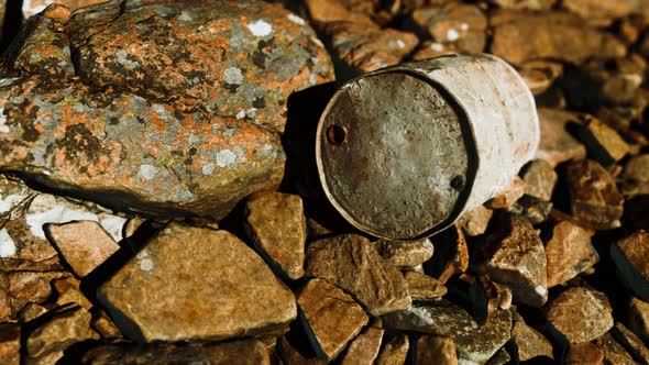 Rusty Destroyed Metal Barrel on Beach Rocks