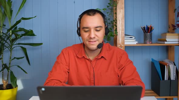 Smiling Businessman Wear Wireless Headset Making Conference Video Call on Laptop