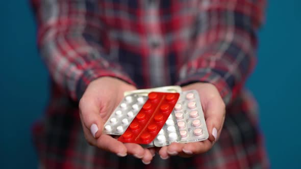 Woman Presenting a Handful of Foil-wrapped Pills