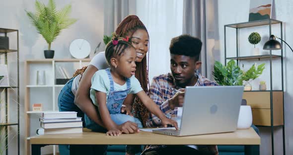 African Parents with Daughter Playing Games on Laptop