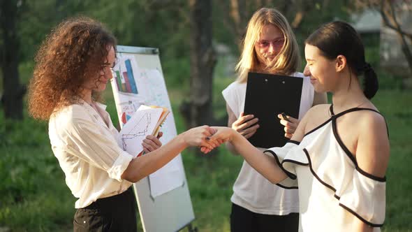 Young Positive Colleagues Greeting Shaking Hands in Slow Motion Talking at Golden Sunset in Park