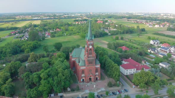 Church in Small City Among Pastures. Drone Footage. Red Church Is Roman Catholic Church.
