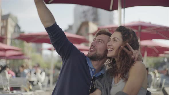 Couple at sidewalk cafe posing for selfie