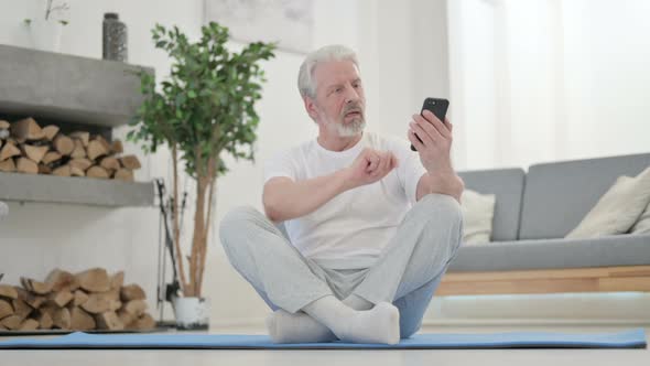 Old Man Using Smartphone on Yoga Mat at Home