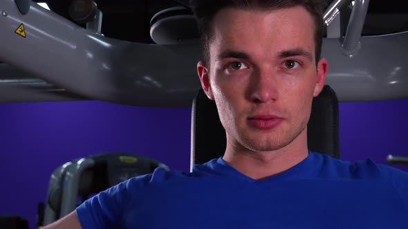 A Young Fit Man Trains on a Machine in a Gym - Closeup