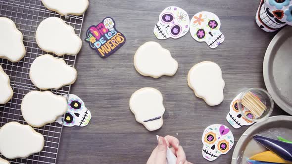 Step by step. Flat lay. Decorating sugar skull cookies with different color royal icing.