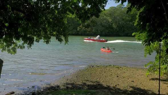 River view with man in canoe and motor boats