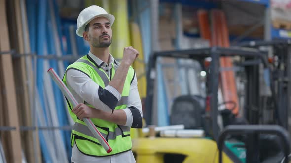 Thoughtful Young Middle Eastern Man Crossing Hands Turning to Camera Smiling Standing in Industrial