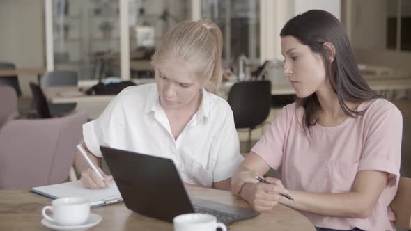 Focused Blonde Woman Writing Something on Paper with Pen