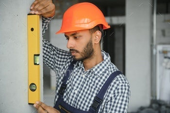 Indian construction site manager standing wearing helmet, thinking at construction site.