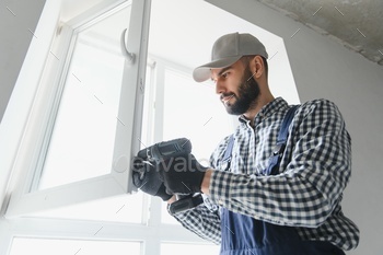 service man installing window with screwdriver