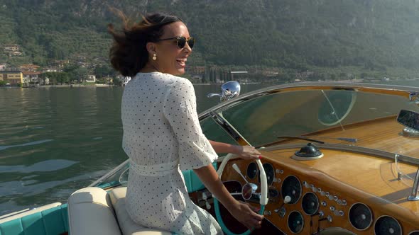 A woman on a classic luxury wooden runabout boat on an Italian lake
