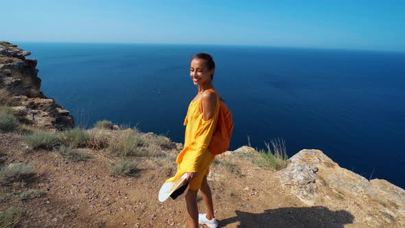 Woman Yellow Sundress Enjoying View of Seashore and Bay Standing on Precipitous Coastline