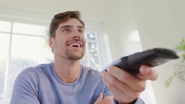 Young man laughing while watching television at home 