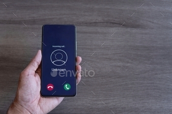 Top view image of hand holding smartphone and unknown incoming phone call on the screen.