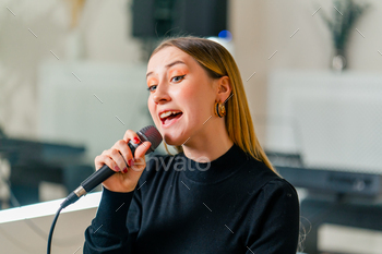 young girl sings in a vocal lesson with a microphone in her hands during a lesson at a music school
