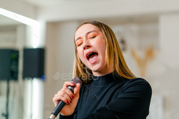 young girl sings in a vocal lesson with a microphone in her hands during a lesson at a music school