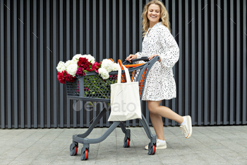 A beautiful girl with a cart with flowers on the street.