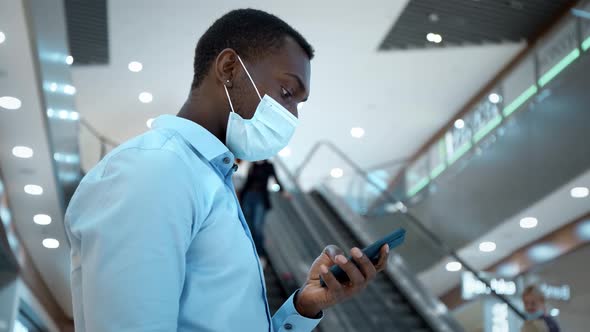 A Man in a Protective Mask During an Epidemic Remains in Touch on the Internet on His Smartphone