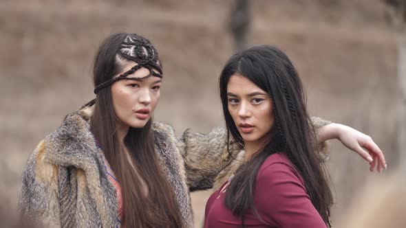 two Asian young women in ethnic clothes posing in the steppe in nature. Slow motion.