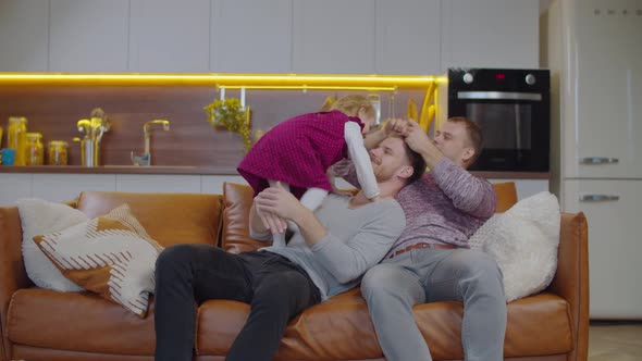 Joyful Lgbt Parents and Kid Resting on Sofa