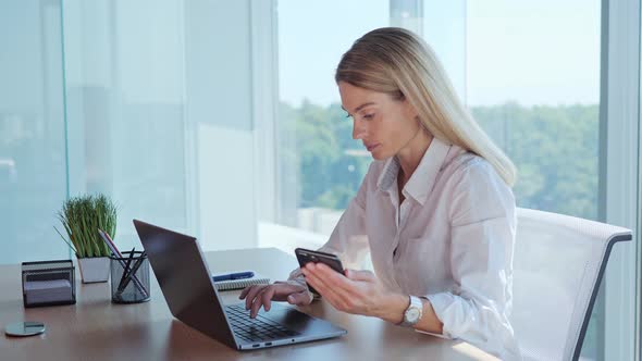 An Office Worker Makes a Calculation a Financial Report Uses Phone and Laptop