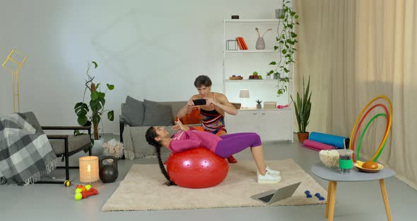 Slender Girl Trainer Lies on Back on Red Sports Ball Doing Exercises Training with Fitball at Home