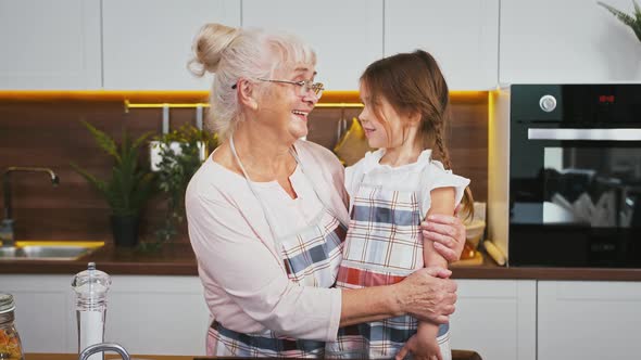 Senior Granny and Her Little Granddaughter are Looking at Each Other Hugging and Smiling While