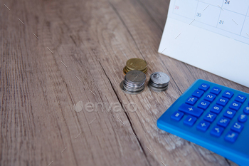 Closeup image of calculator, calendar and coins.