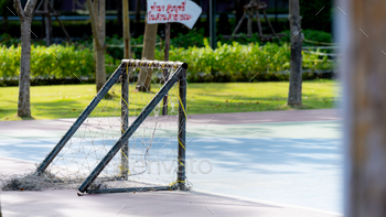 A small futsal goal stands on a practice field, in a public park,