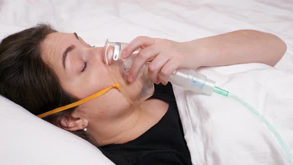 Young Woman in a Mask Lies on the Bed and Begins To Cough and Gasp