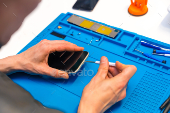 Man repairing a mobile phone in small workshop